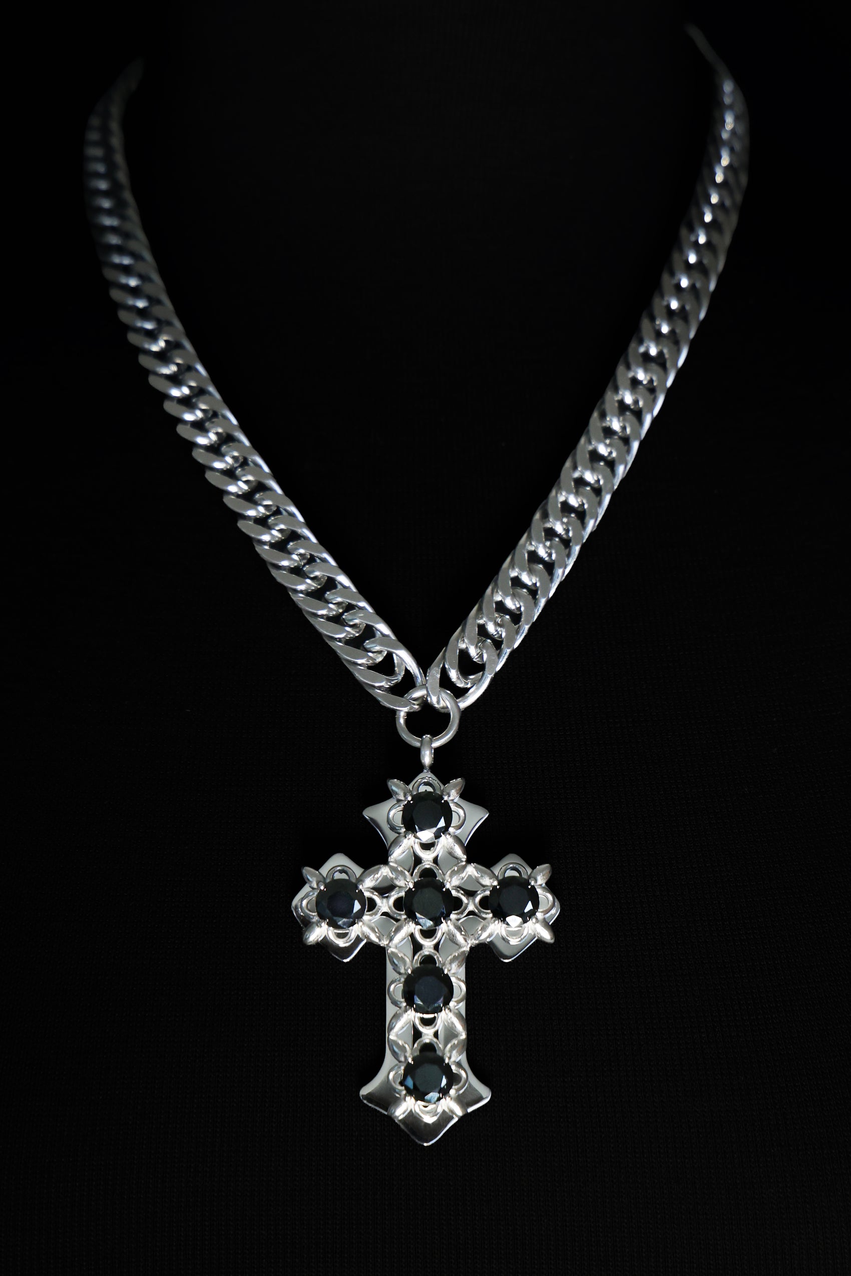 Silver chain necklace with a cross pendant on a black background